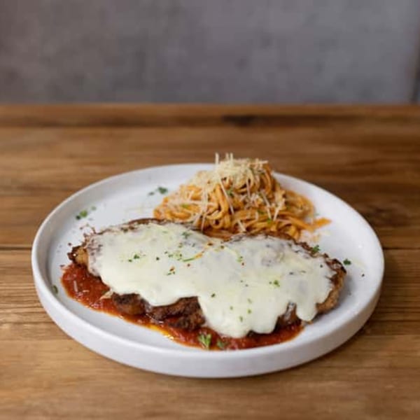 Chicken Parmesan with melted mozzarella and a side of spaghetti with red sauce and grated cheese.