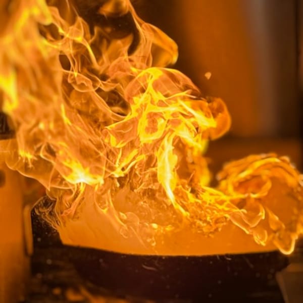 Flames erupting from a pan, suggesting a cooking process at Andiamo Italian Grill.